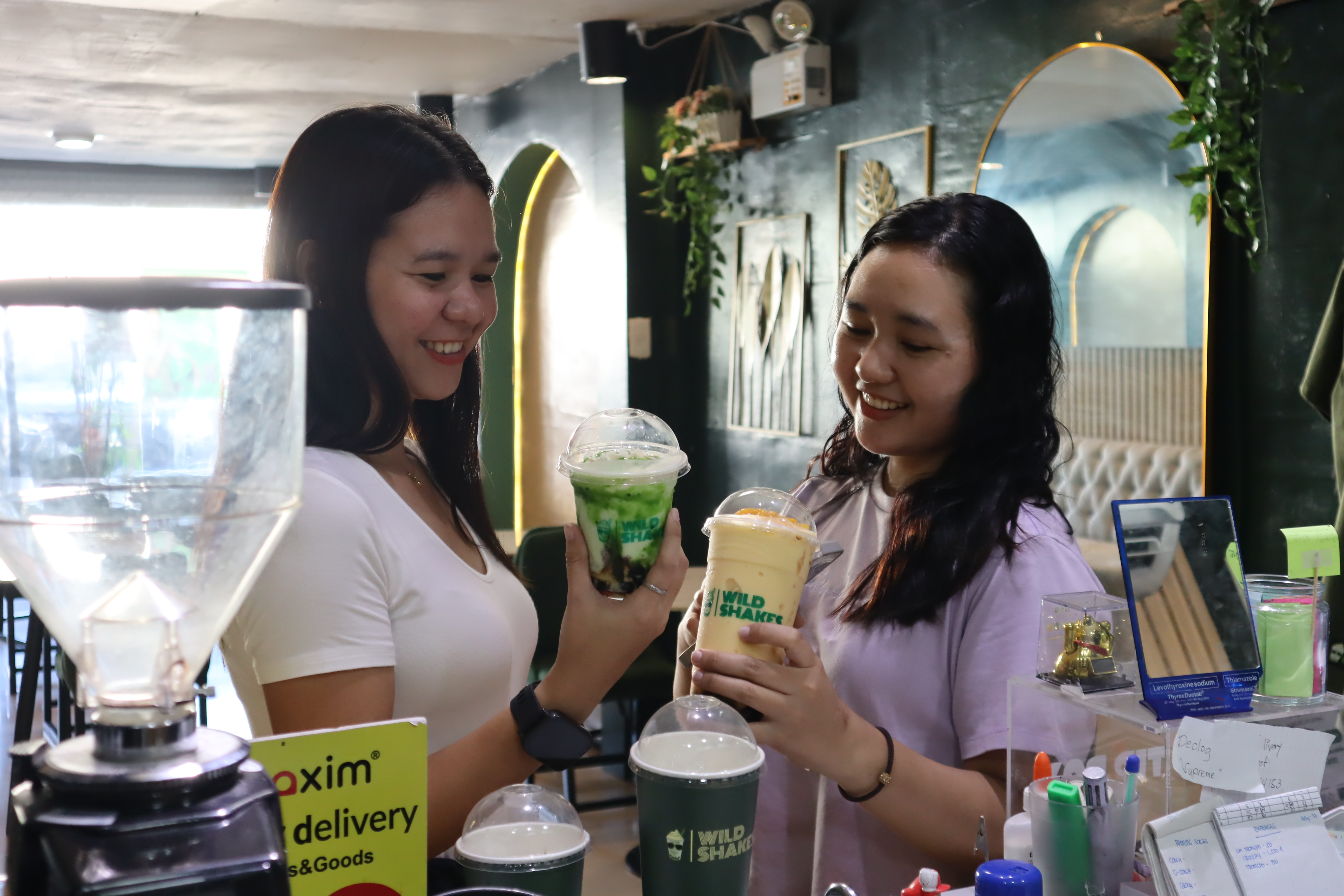 Wild Shakes staff holding branded shakes behind the counter